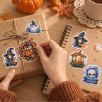 Hände dekorieren ein Geschenk mit Halloween Stickern