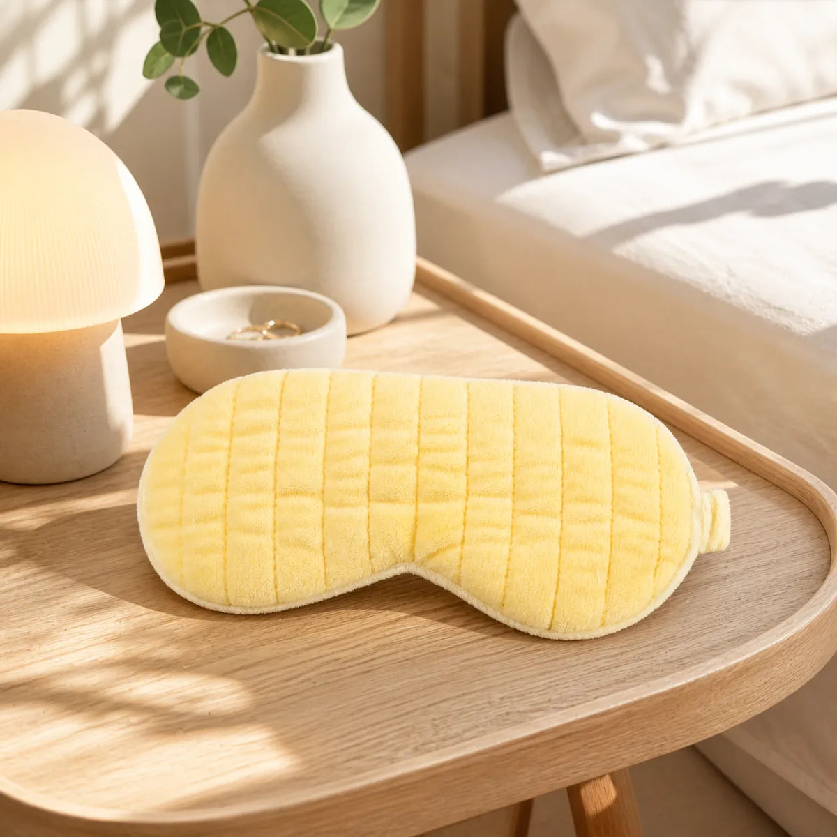 Gelbe MUMUSO Schlafmaske mit Steppstruktur auf einem Holztisch im Schlafzimmer