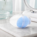 Hellblauer Make-up Schwamm in Wassertropfenform mit Aufbewahrungsbox auf einem hellen Schminktisch
