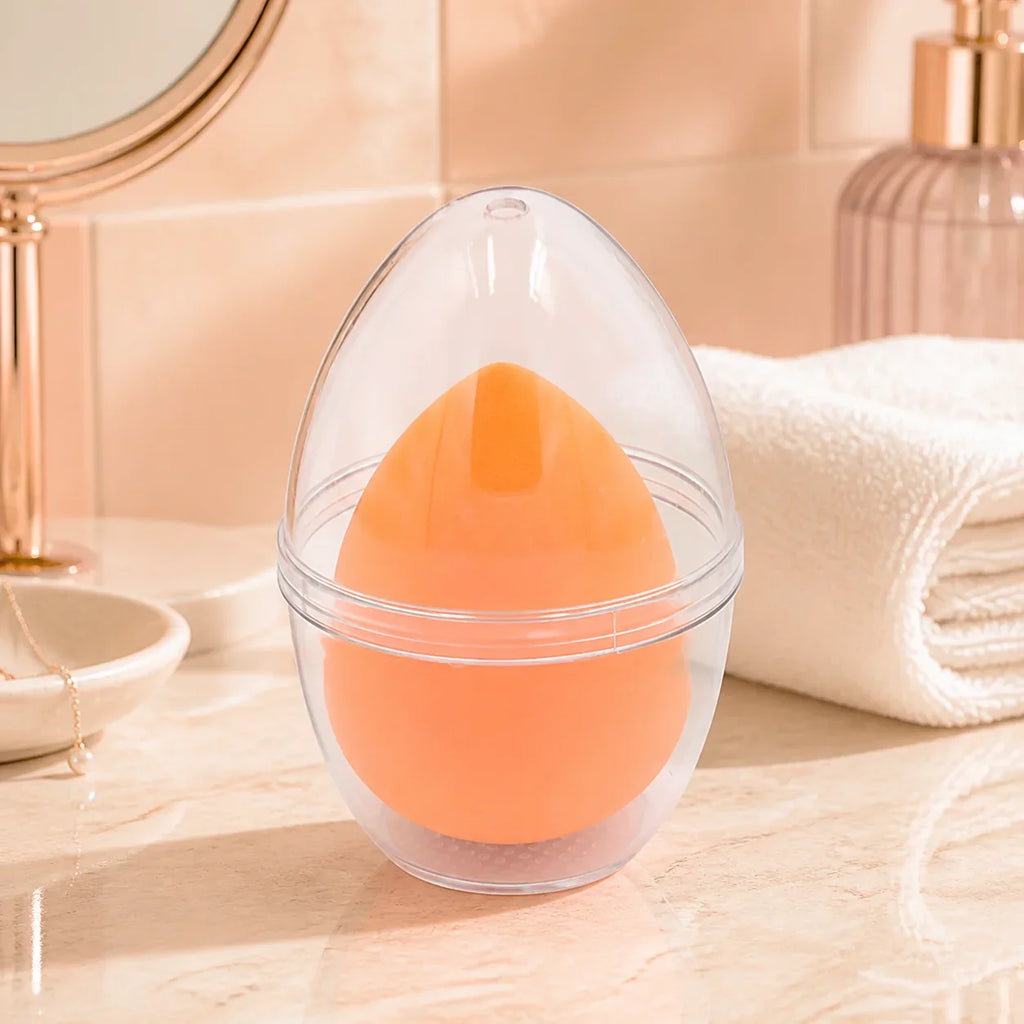 Oranger Make-up Schwamm in Tropfenform mit Aufbewahrungsbox auf einem Schminktisch