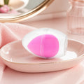 Rosa Make-up Schwamm in Tropfenform mit Aufbewahrungsbox auf einem Schminktisch