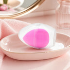 Rosa Make-up Schwamm in Tropfenform mit Aufbewahrungsbox auf einem Schminktisch