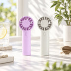 Mini Handventilator in Lila und Weiß auf einem hellen Sommertisch